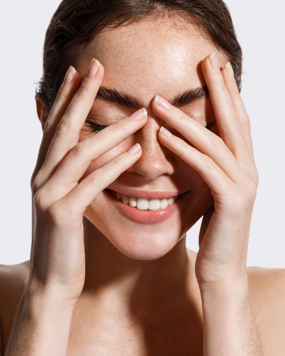 FEMME QUI SOURIT, MAIN SUR LE VISAGE BOPLUME DERMATOLOGIE